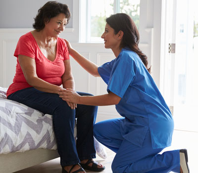 Care home bedroom with elderly lady and care worker - What makes a safe home for the elderly?