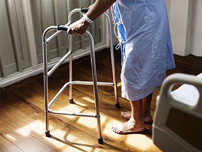 Elderly person walking with aid protected with care home insurance