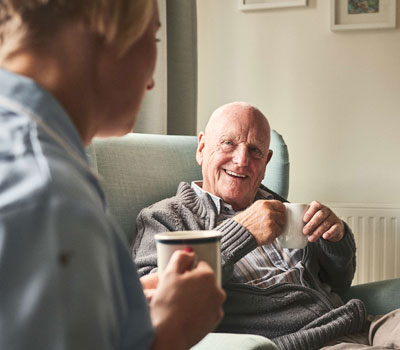 Male resident having a cup of tea with NHS workers