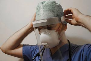 nhs frontline worker wearing equipment that firefighters have volunteered to assemble face shields 