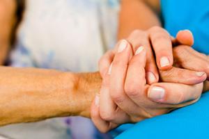 Social care – a nurse holds an elderly patient's hand