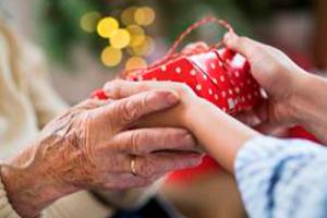 A child giving a woman living with dementia a christmas gift